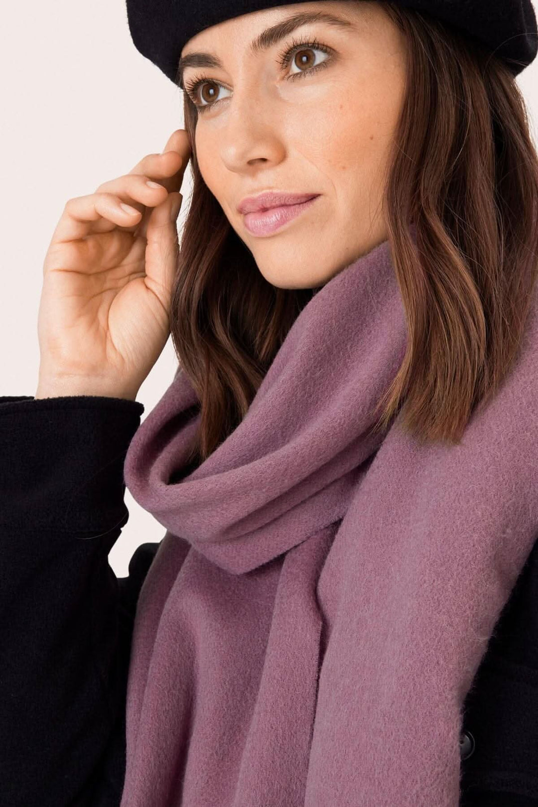 Foulard Anna en laine rose porté par une femme, ajoutant une touche de chaleur à une tenue élégante.