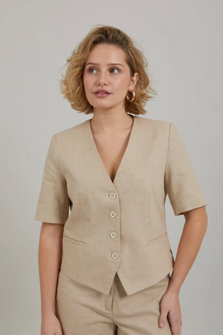 Blazer court à manches courtes beige avec un col V et fermeture boutonnée, idéal pour l'été.
