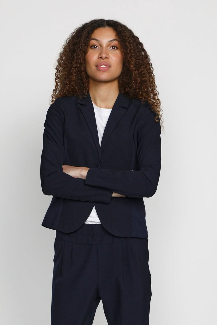 Femme portant un blazer Kajillian bleu marine, élégant et chic, idéal pour le bureau ou un événement.