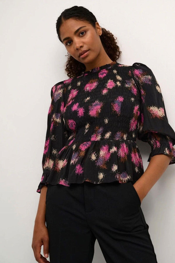 Blouse Lita en noir avec imprimé fuchsia à taches, manches 1/2, coupe ajustée et bas évasé.
