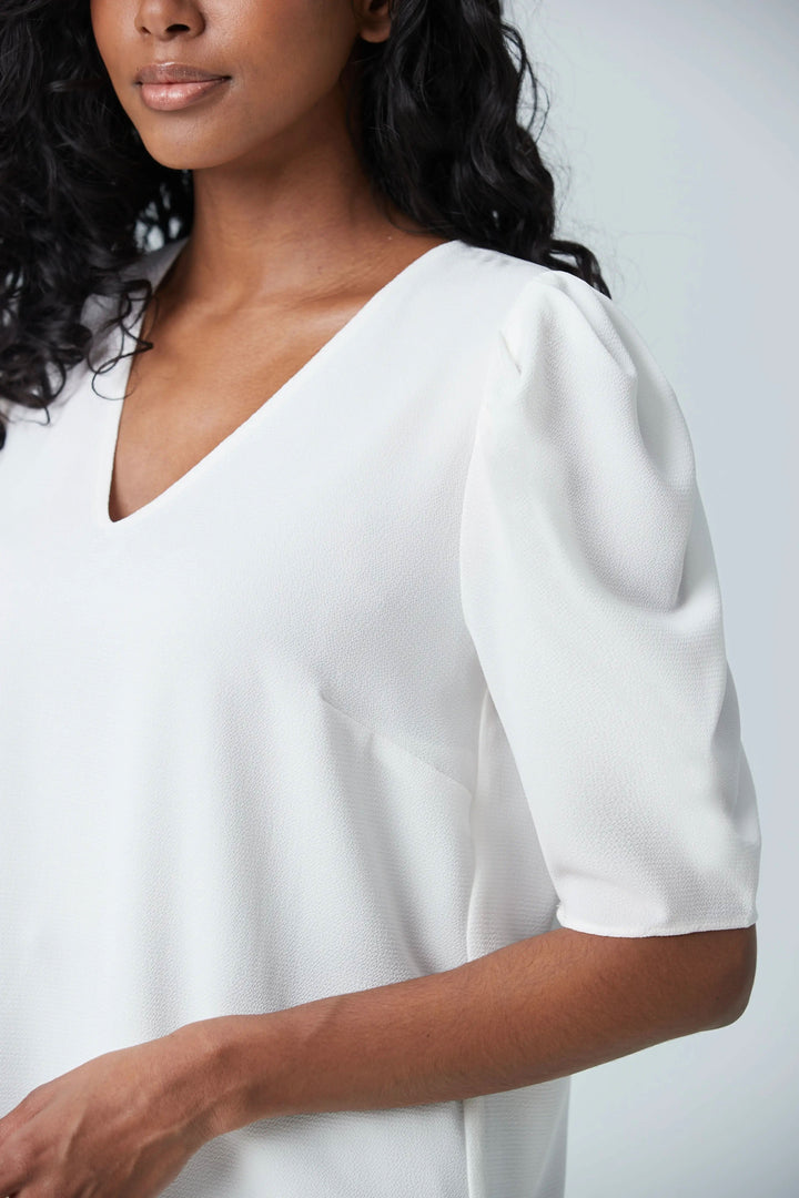 Blouse blanche à manches gigots et col en V, idéale pour le travail ou les sorties, confectionnée en tissu léger.