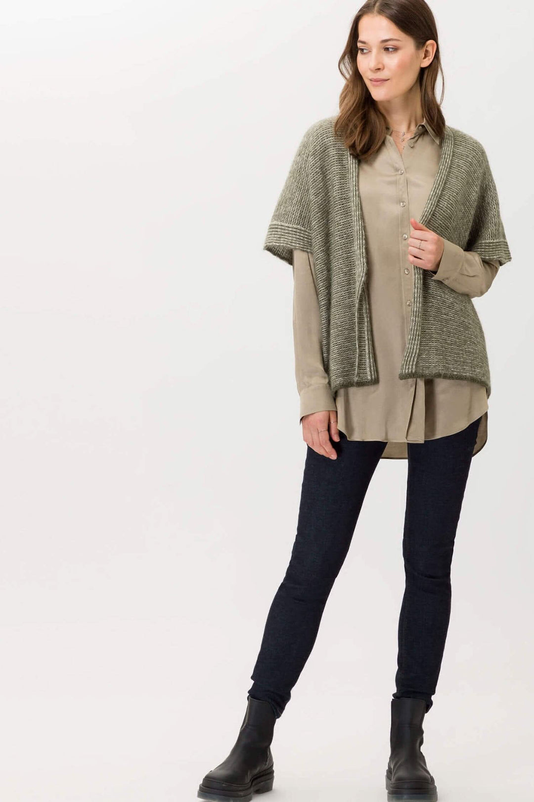 Femme portant un chemisier beige avec un cardigan gris et un pantalon noir, stylé et décontracté.
