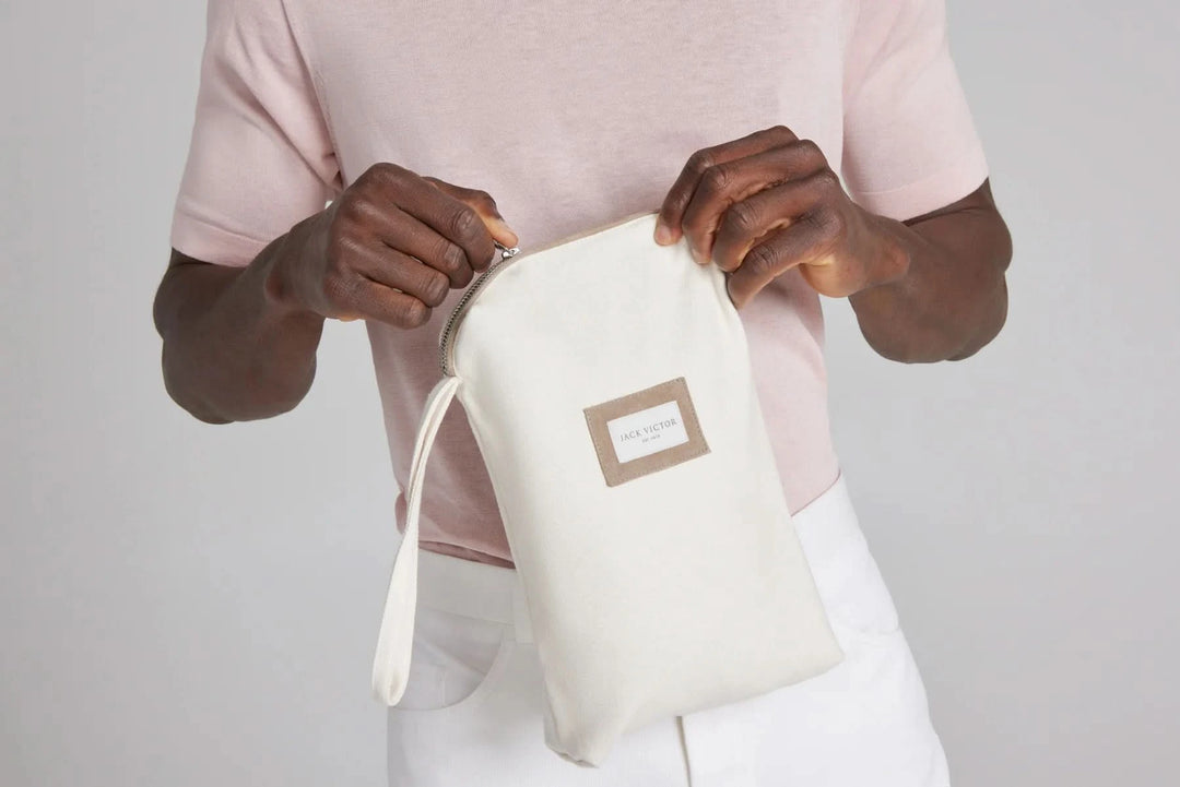 Homme tenant une pochette en coton blanc, accessoire de mode pratique et élégant, idéal pour le rangement.