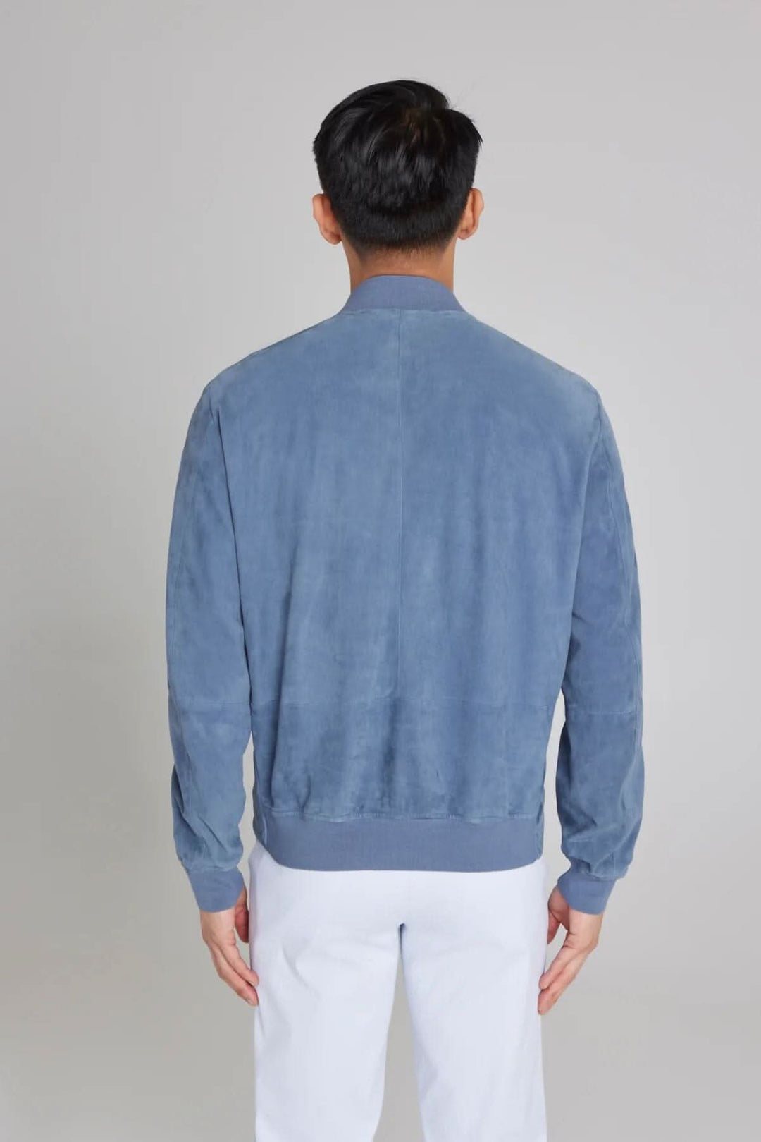 Vue arrière d'un bomber ultraléger en daim bleu, élégant et confortable, idéal pour le voyage.