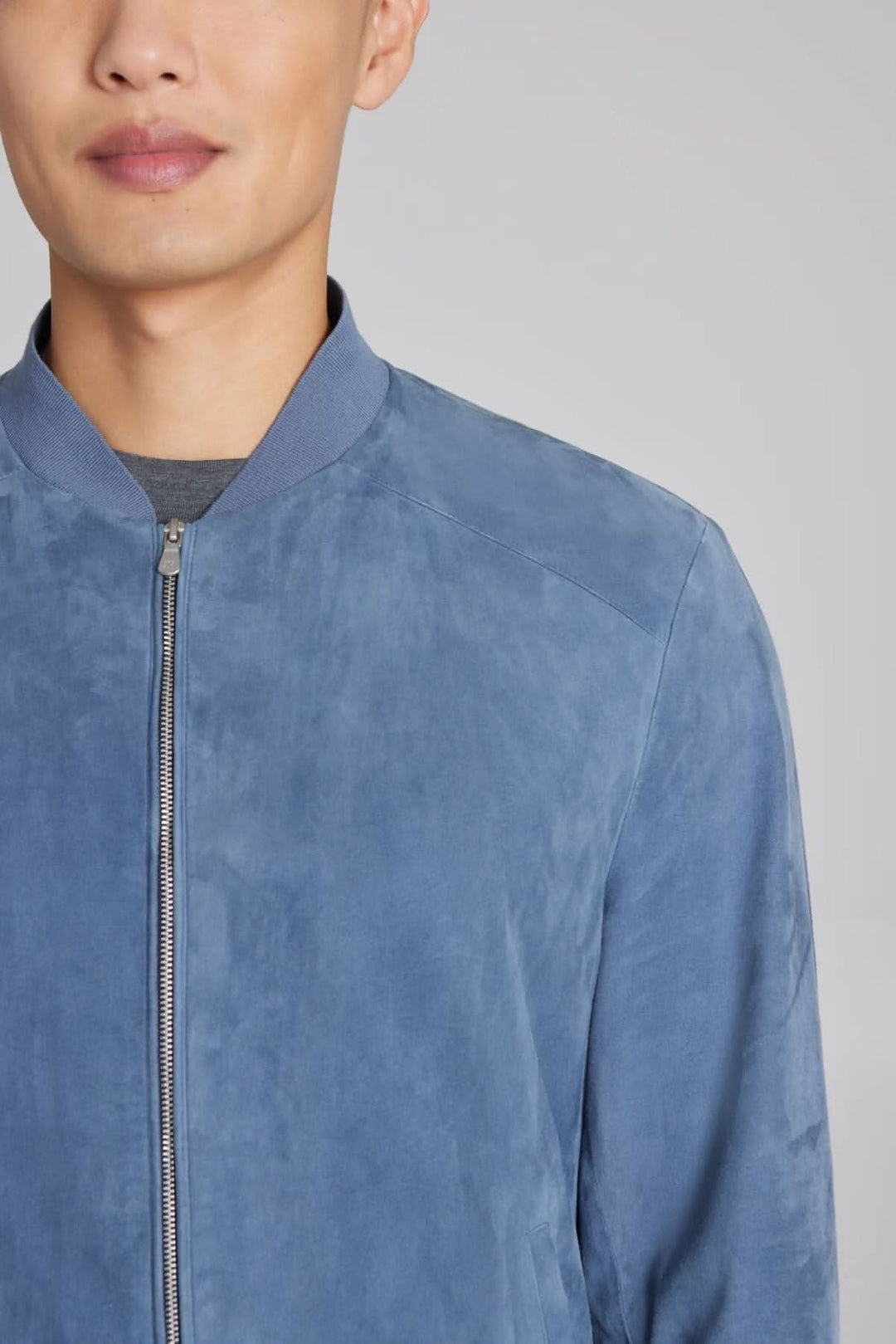 Homme portant un bomber ultraléger en daim bleu, alliant confort et style, idéal pour le voyage.