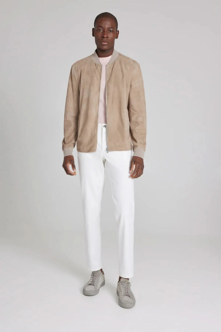 Homme portant un bomber ultraléger en daim beige avec un t-shirt rose et un pantalon blanc, style élégant.