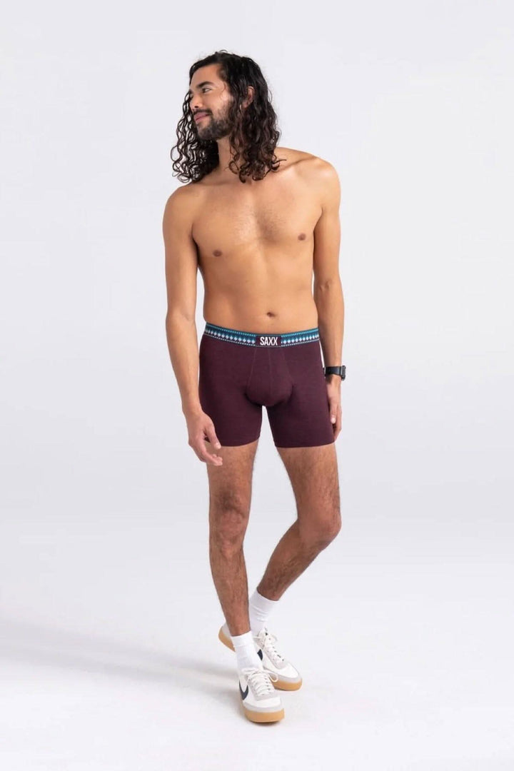 Homme portant des boxers bourgogne SAXX avec une ceinture bleue, affichant un look décontracté.