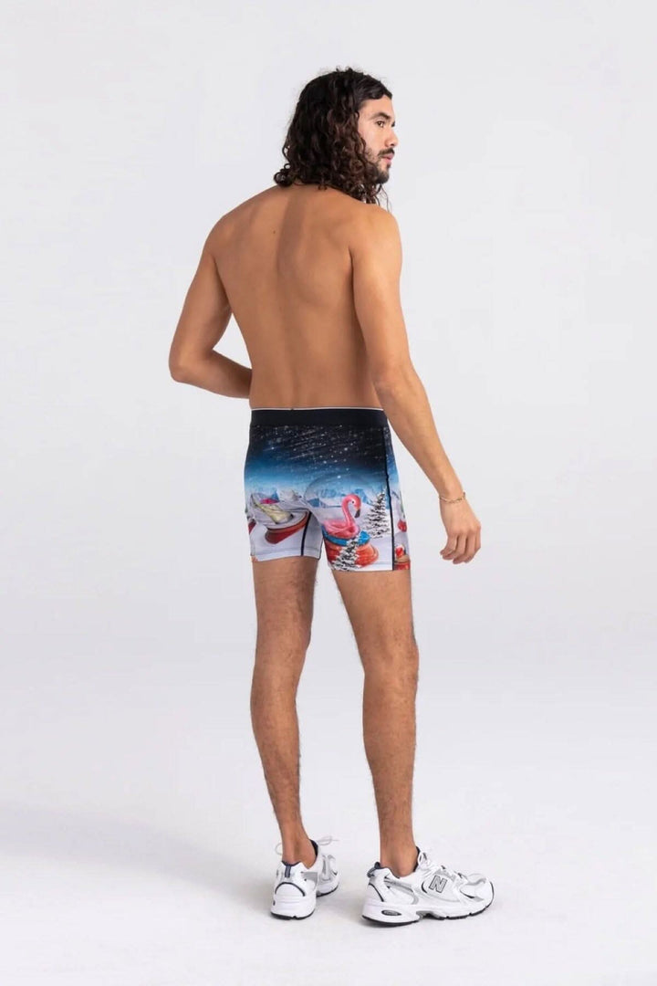 Homme de dos portant des boxers avec motif de flamants roses et parapluies sur fond de neige.