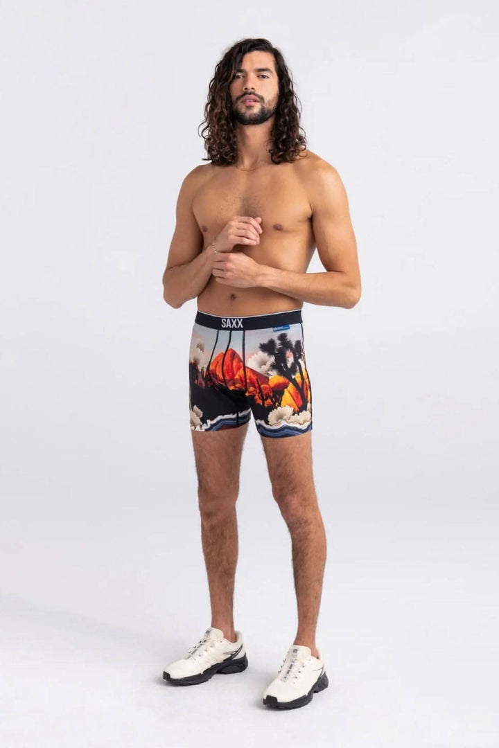 Homme portant des boxers Saxx avec un motif de paysage coloré, adapté pour le confort et les activités sportives.