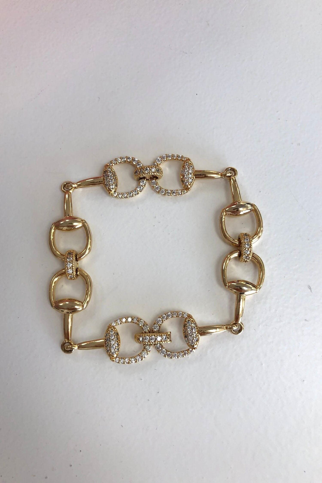 Bracelet doré élégant avec breloques carrées et brillants, idéal pour accessoiriser votre tenue.