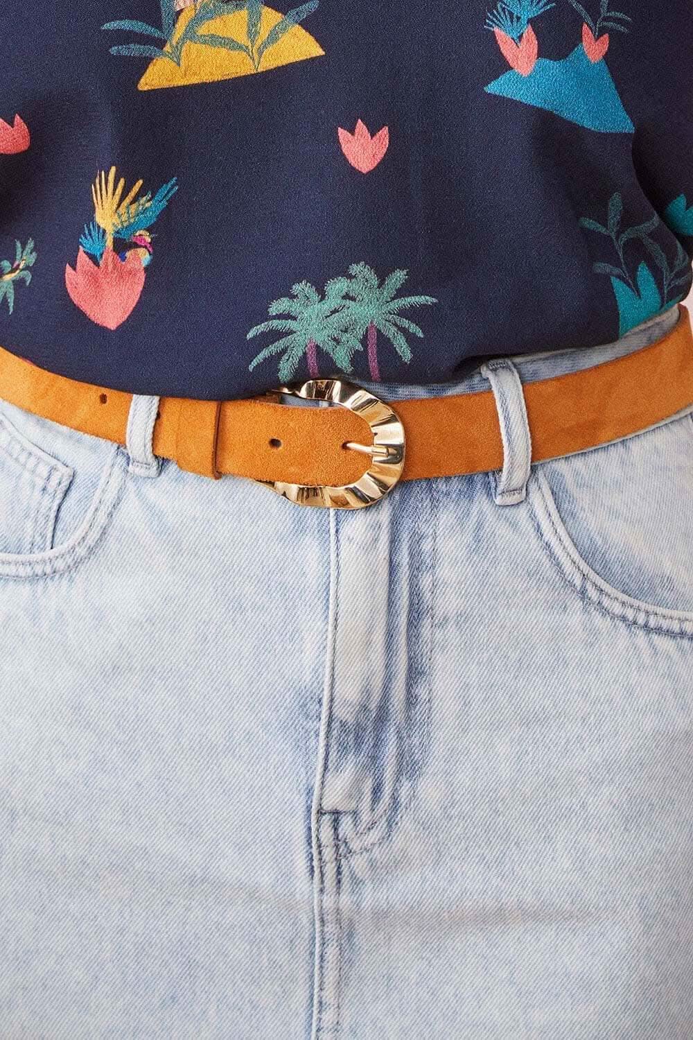 Ceinture en cuir velours cumin avec boucle dorée, portée sur un pantalon en denim, look chic et tendance.