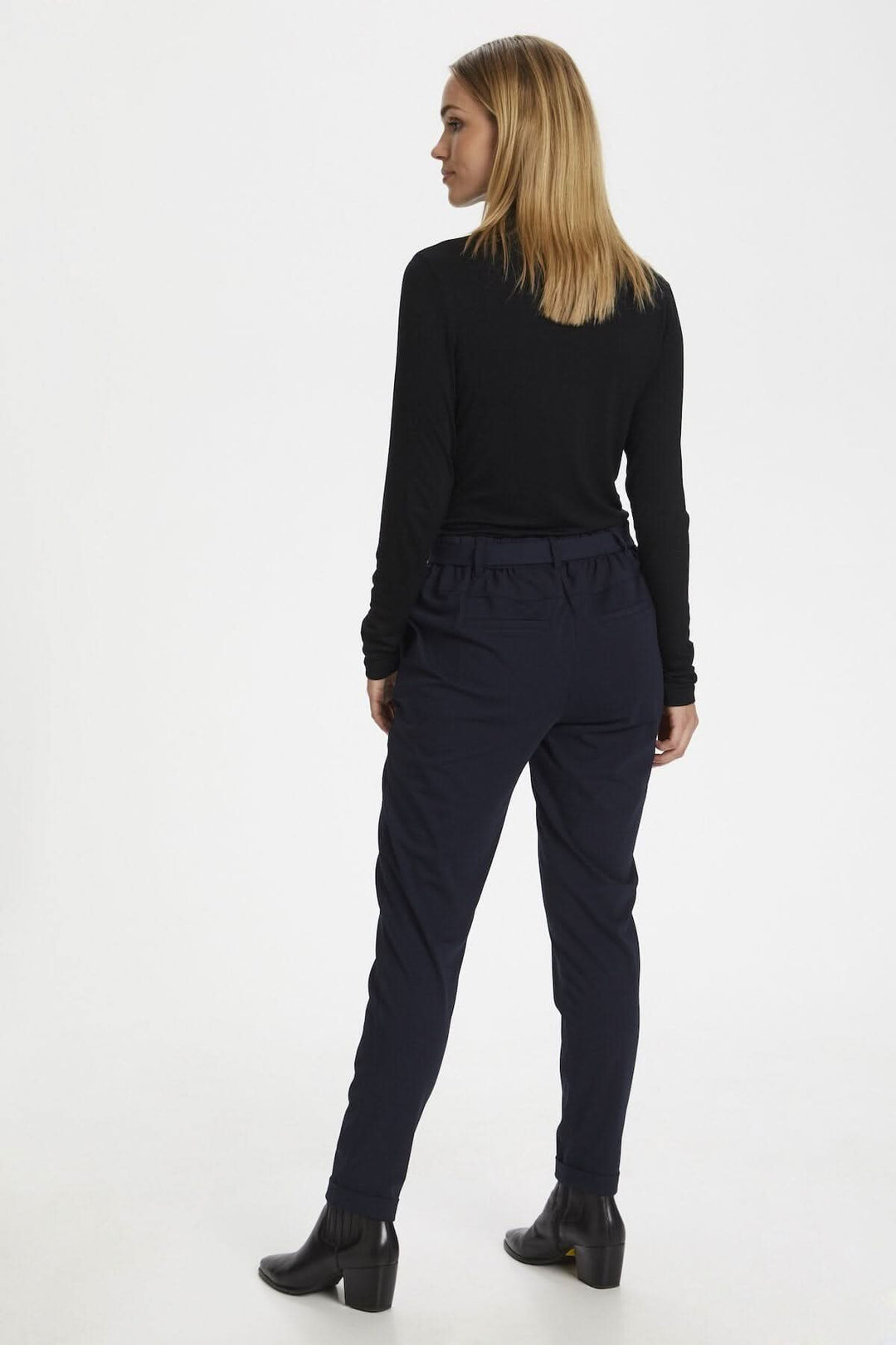 Femme vue de dos portant un chandail noir à manches longues et un pantalon foncé.