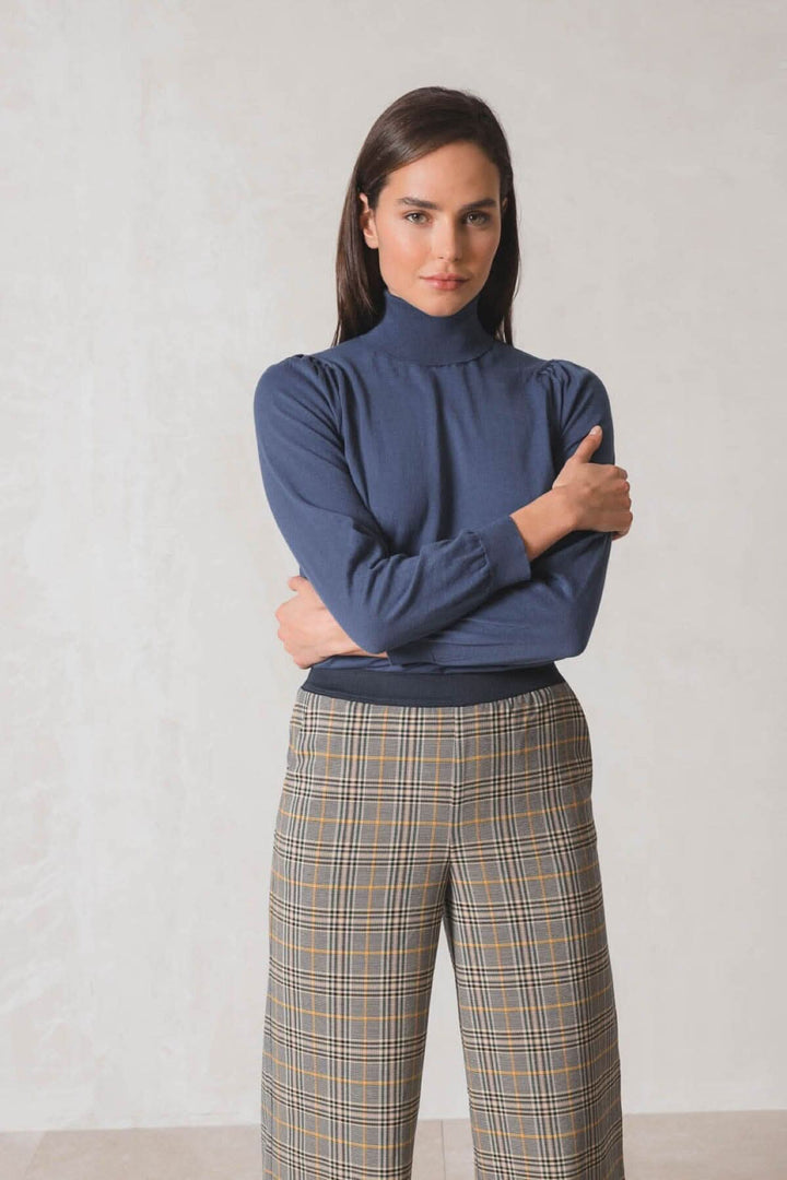 Chandail col roulé bleu avec manches longues, associé à un pantalon à carreaux, modèle prêt pour toute occasion.