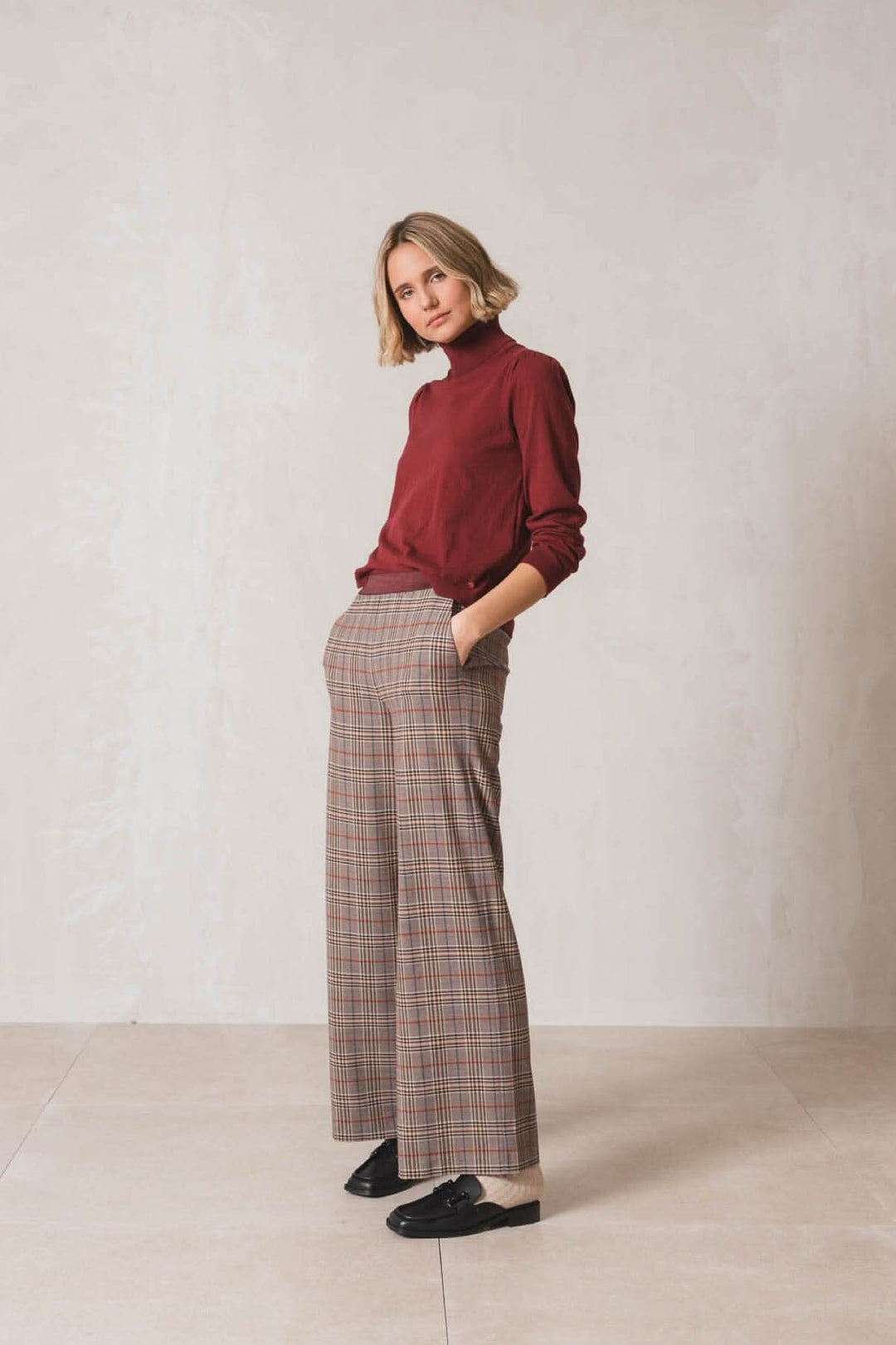 Chandail col roulé bordeaux avec pantalon à carreaux, coupe régulière, manches longues et plis aux épaules.