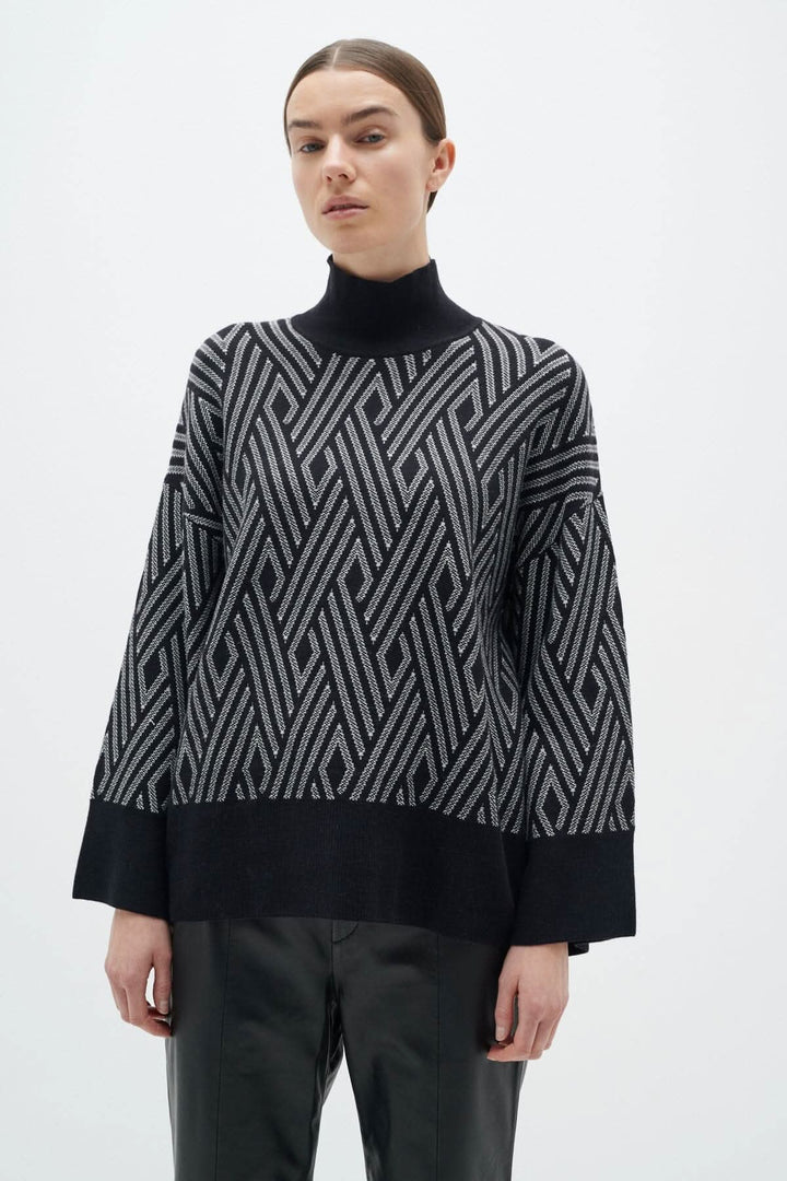 Chandail ample Gittel avec col montant et motif géométrique noir et blanc, parfait pour un look chic et moderne.