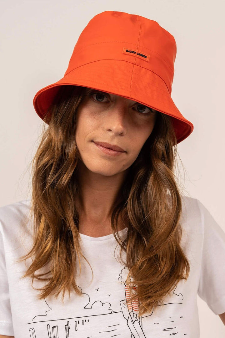 Femme portant un chapeau bob orange waterproof, parfait pour les jours de pluie.