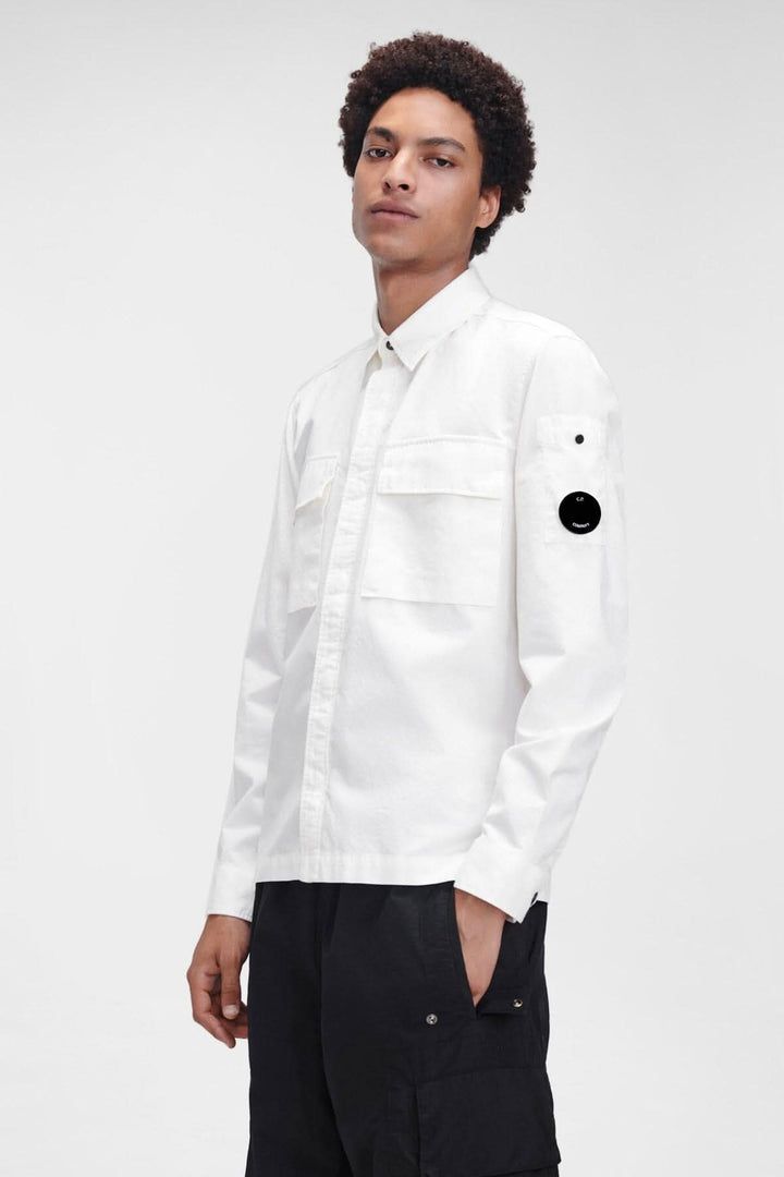 Chemise Batavia blanche à manches longues avec poches sur poitrine et manche, détail en forme de verre de lunette.