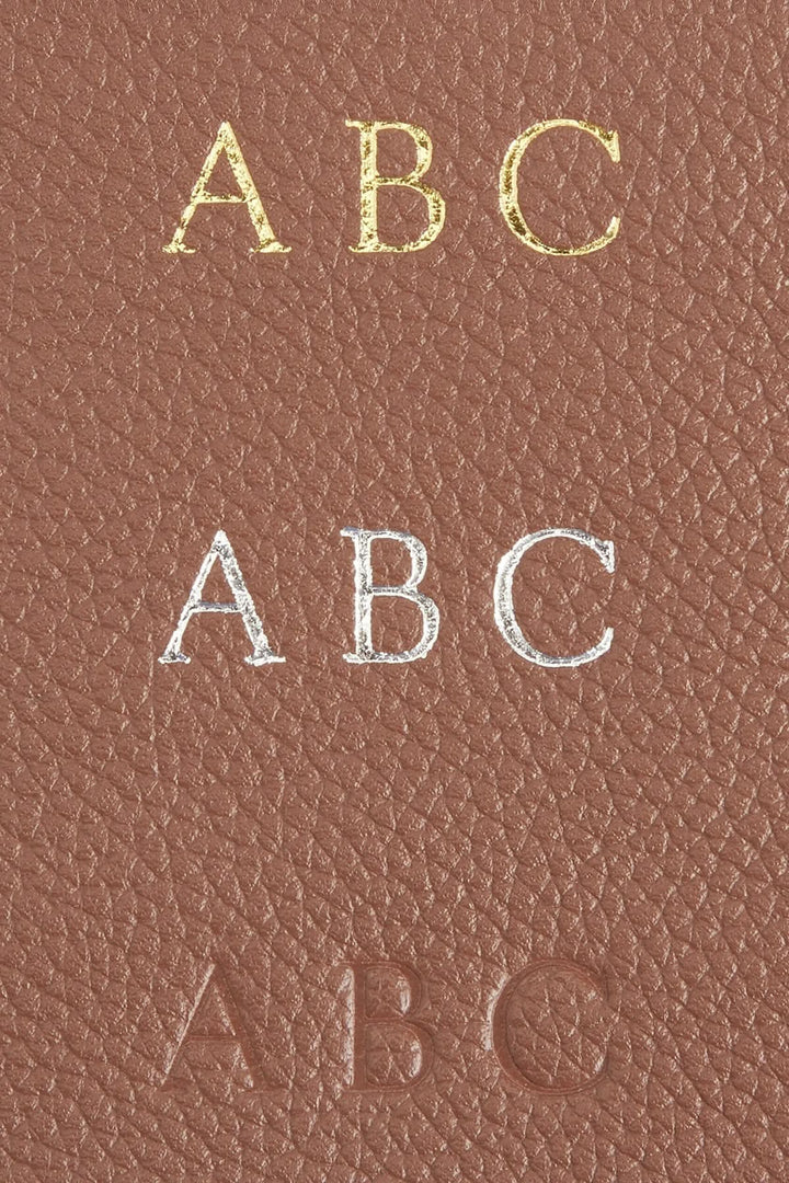 Détails de monogrammes personnalisés en cuir sur un classeur à anneaux, incluant lettres dorées, argentées et en relief.