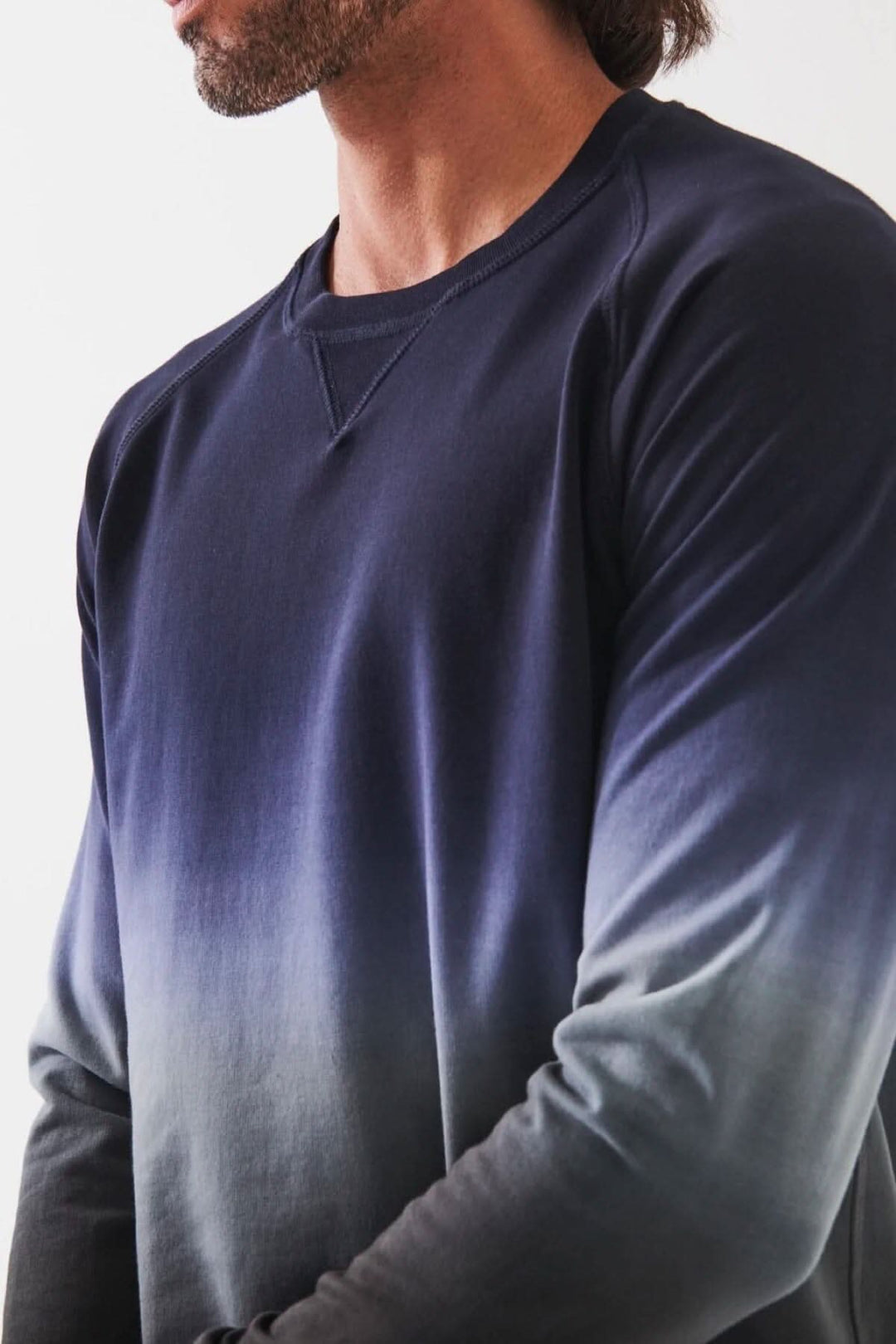 Homme portant un col rond en coton dégradé bleu, avec une coupe décontractée et poignets côtelés.
