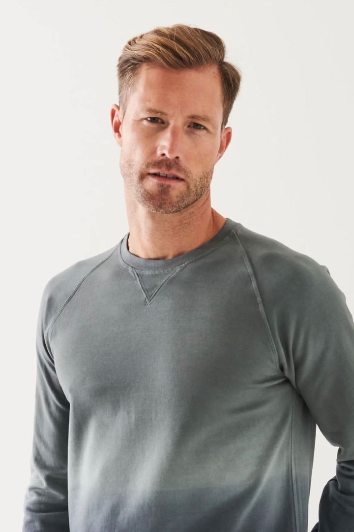 Homme portant un col rond en coton dégradé, coupe décontractée, couleur gris, avec un look moderne et élégant.