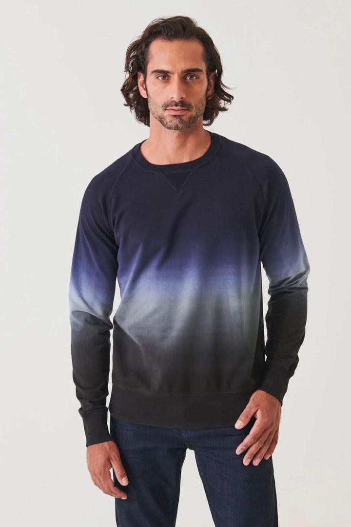 Homme portant un col rond en coton dégradé bleu marine, coupé décontracté avec poignets côtelés.
