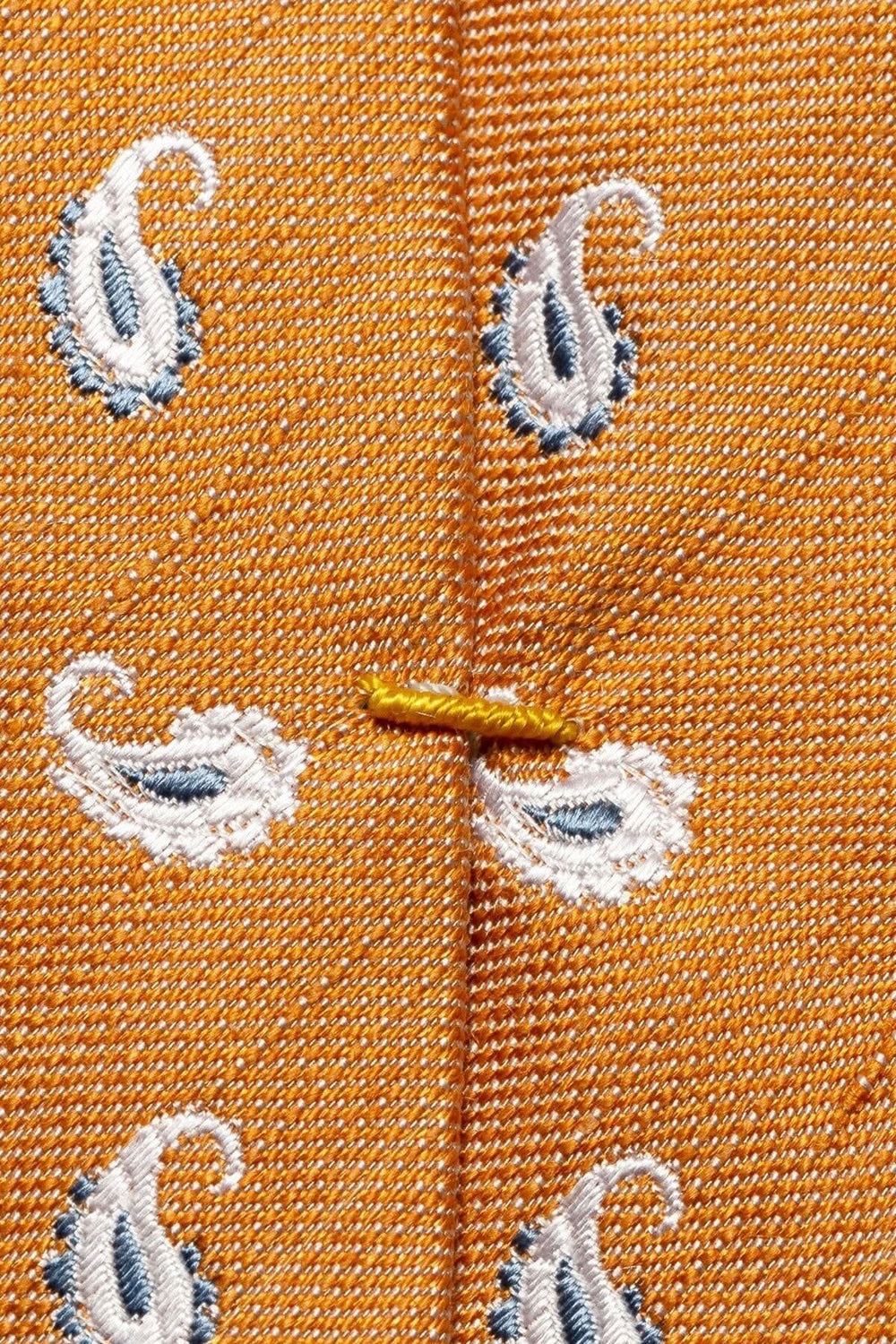 Détail de cravate en soie orange avec motifs paisley bleu et blanc, tissé à la main.