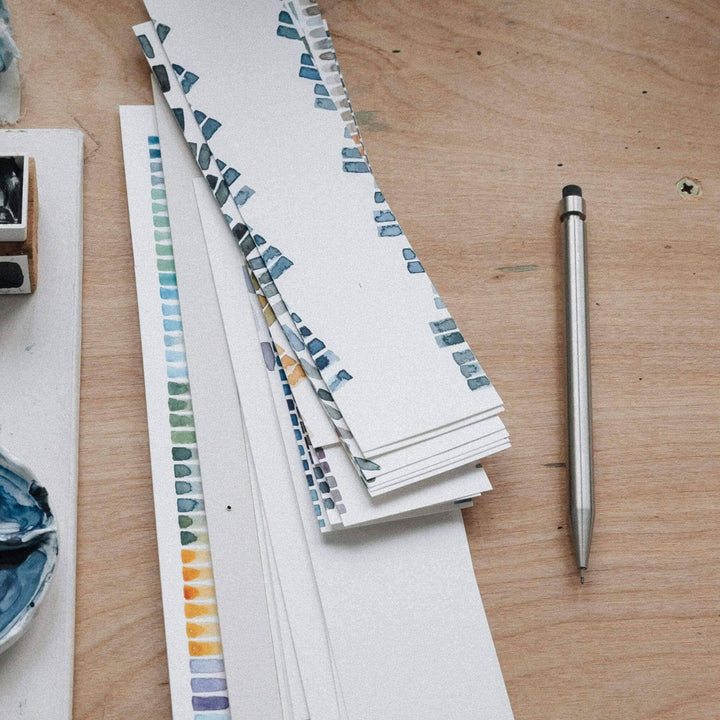 Vue d'ensemble de planches de papier avec des nuances et un crayon Modern Fuel sur une table en bois.