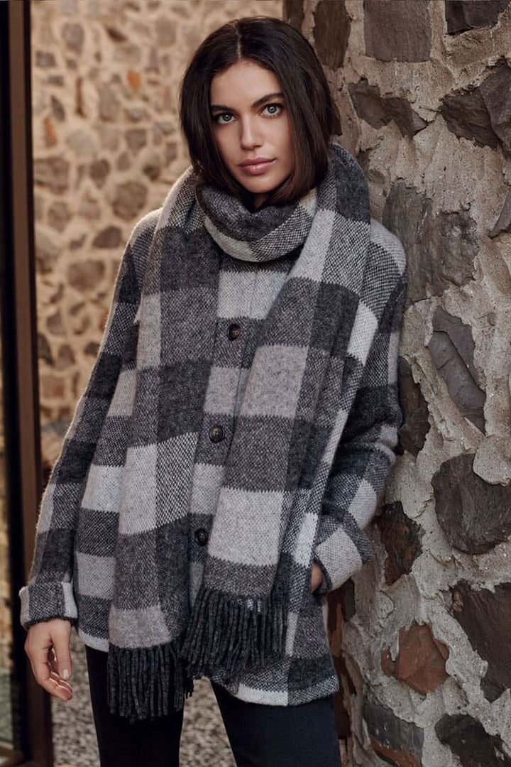 Foulard à carreaux gris et beige avec franges, porté par une femme, style élégant et moderne.