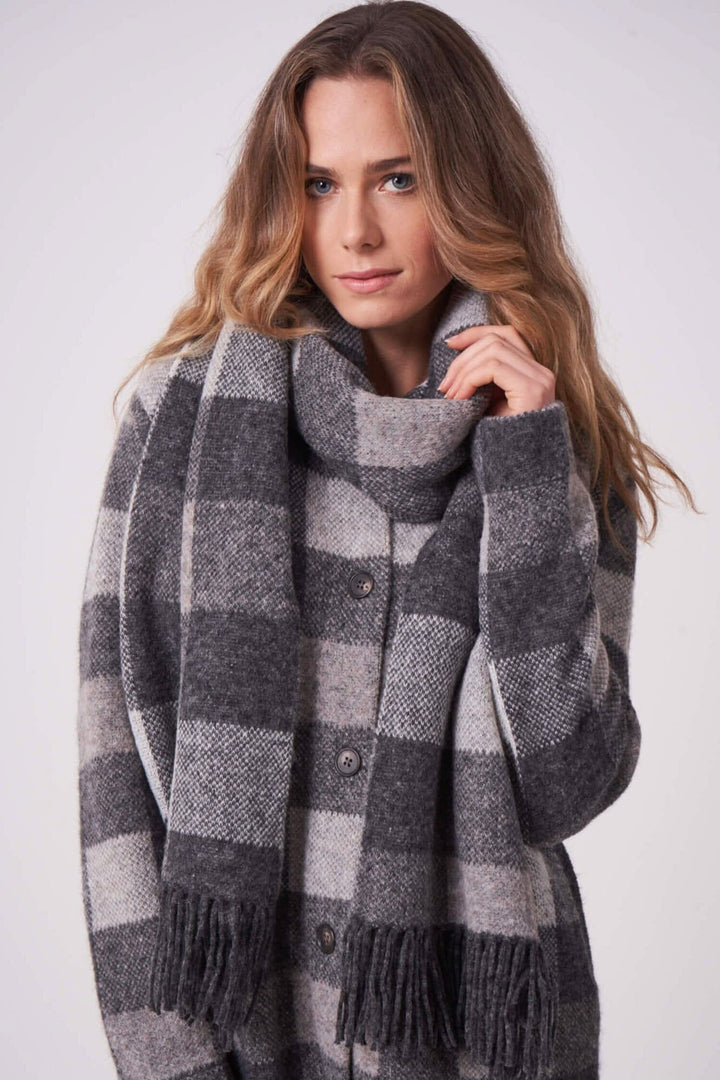 Foulard à carreaux gris et beige avec franges, porté par une femme, style élégant et moderne.