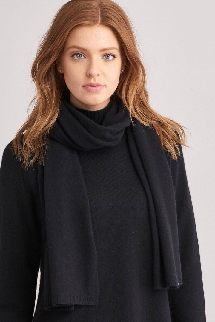 Foulard droit en cachemire noir porté avec un pull, statue élégante et moderne.