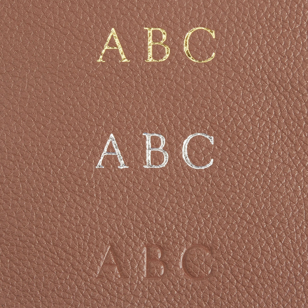 Monogram personalization on leather golf accessory bag showcasing gold, silver, and embossed initials.