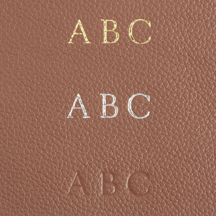 Monogram personalization on leather golf accessory bag showcasing gold, silver, and embossed initials.