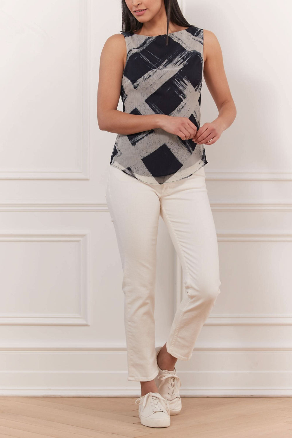 Haut sans manches imprimé au design texturé, porté avec un pantalon blanc, style élégant et décontracté.