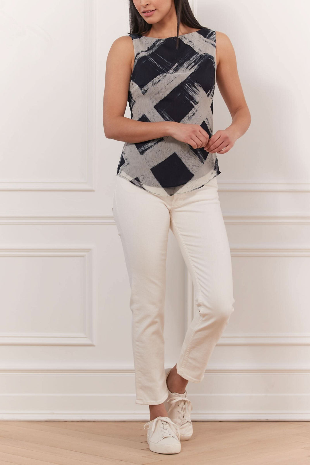 Haut sans manches imprimé au design texturé, porté avec un pantalon blanc, style élégant et décontracté.