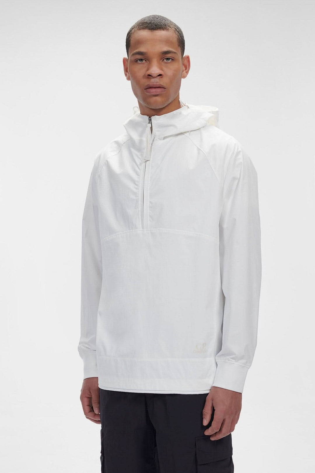 Homme portant un sweat-shirt à capuche blanc avec demi-fermeture zippée et logo C.P. Company.