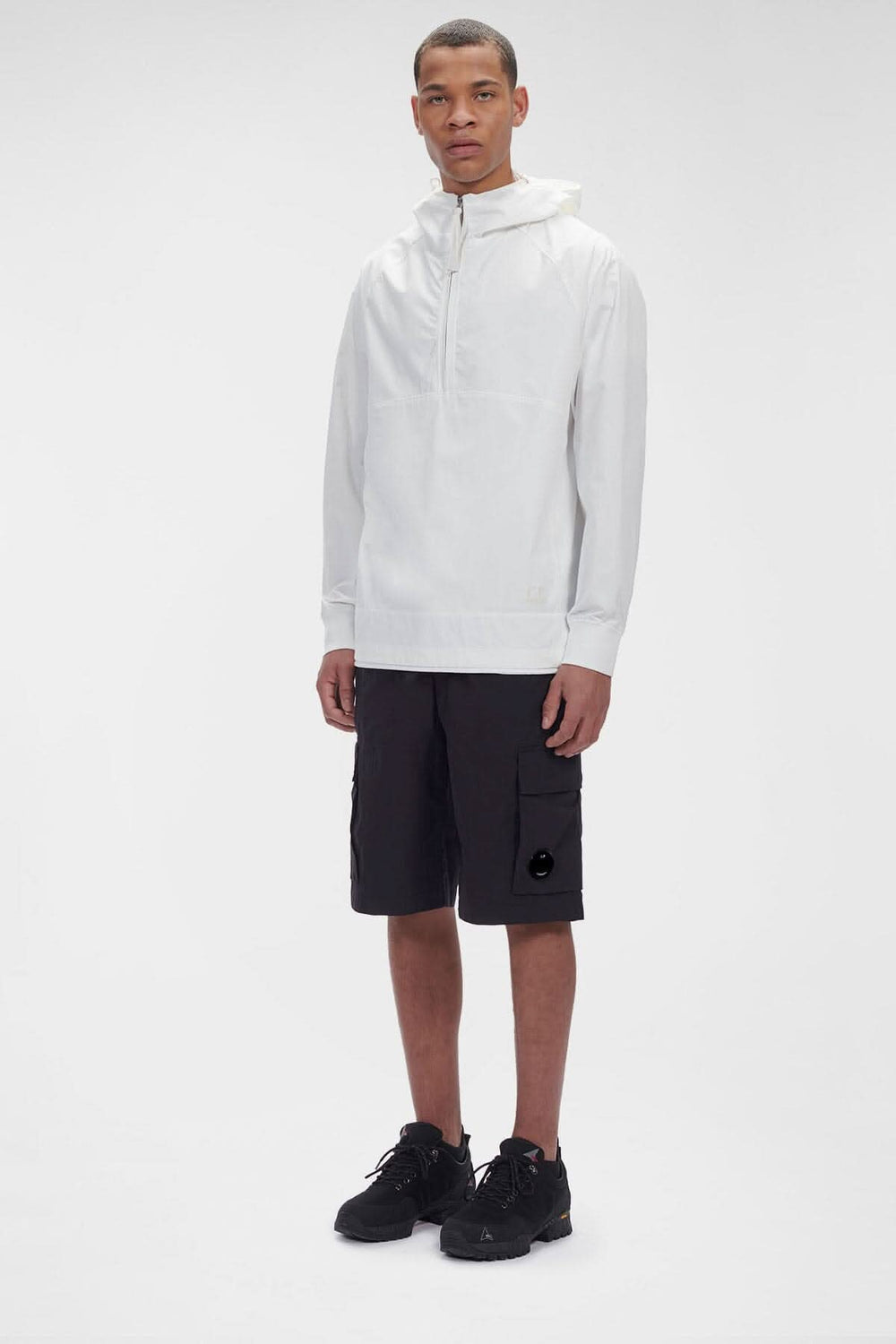 Homme portant le hoodie Dyshell en nylon bi-stretch, avec pantalons cargo noirs et sneakers, style décontracté.