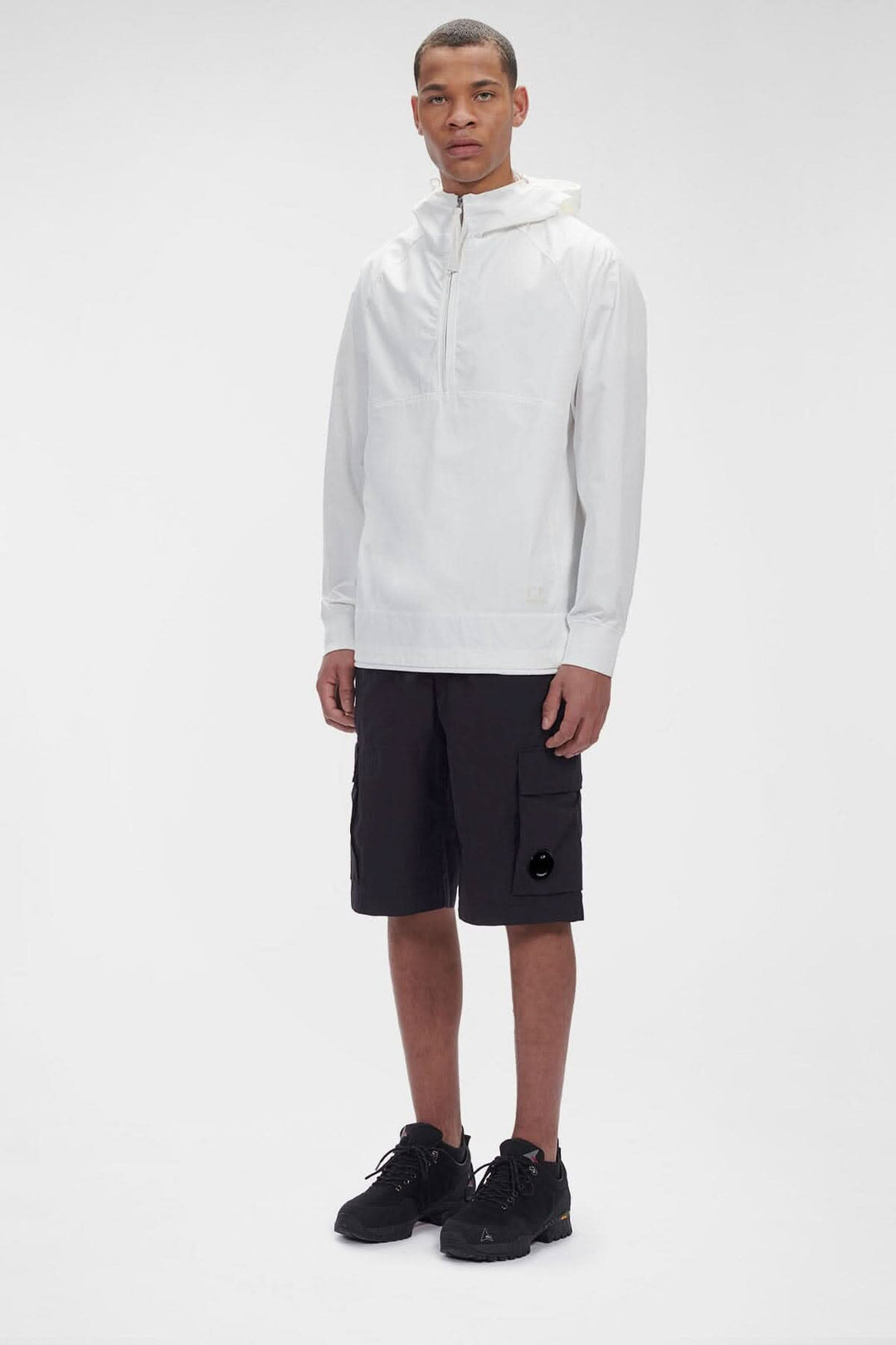 Homme portant le hoodie Dyshell en nylon bi-stretch, avec pantalons cargo noirs et sneakers, style décontracté.