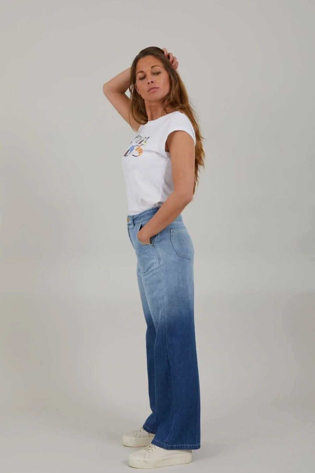 Jean à jambes larges taille haute avec un haut blanc, mannequin posant de profil.