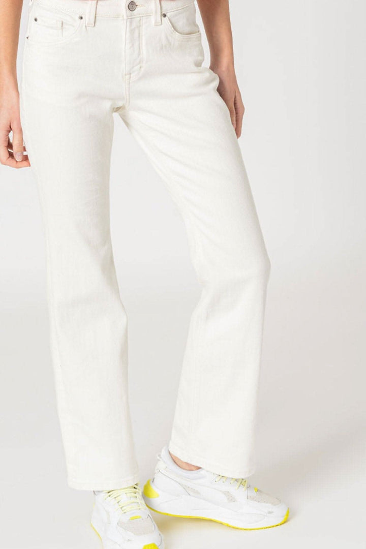 Jean bootcut blanc avec cinq poches, jambe ajustée et coupe évasée, porté avec des sneakers blanches.