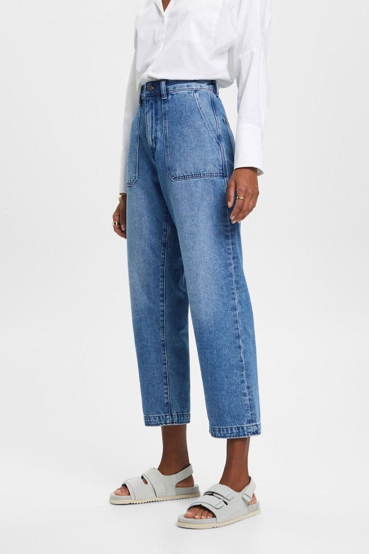 Jean coupe Dad en denim bleu, style décontracté, porté avec une chemise blanche oversize et des sandales.