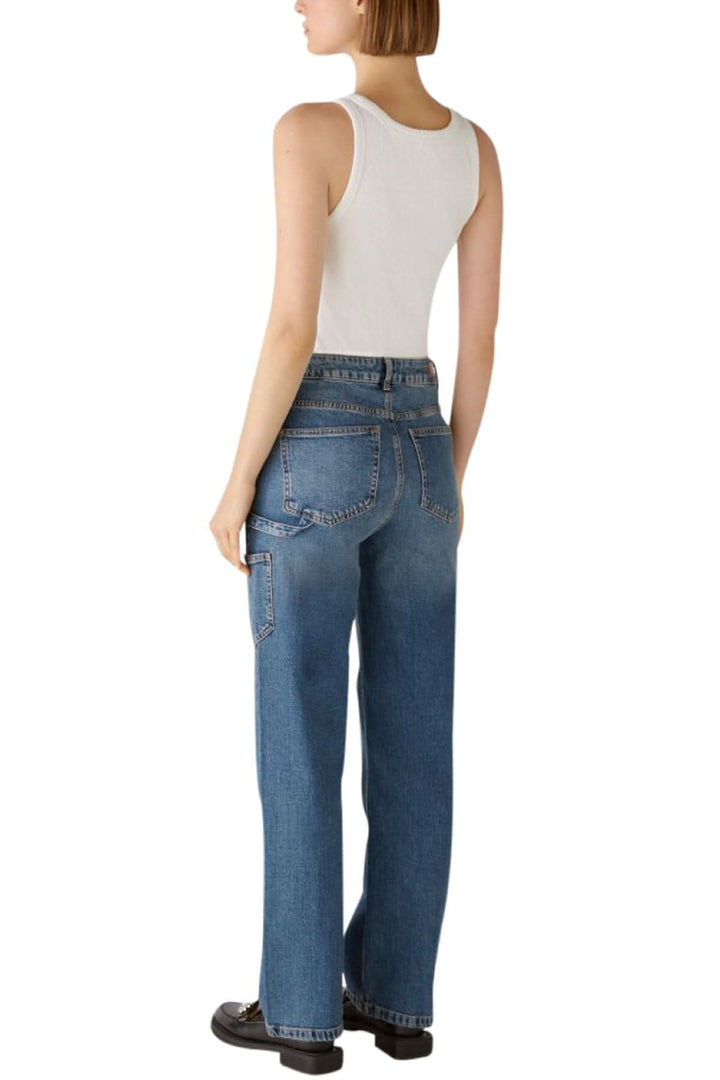 Femme portant un jean coupe droite, vu de dos, avec un haut sans manches blanc.
