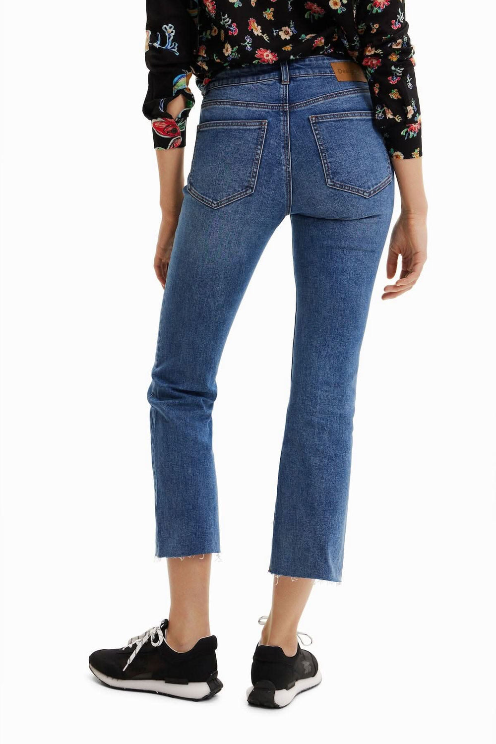 Jean court évasé à broderie florale, vue arrière, intégré avec un haut à fleurs, chaussure noire.