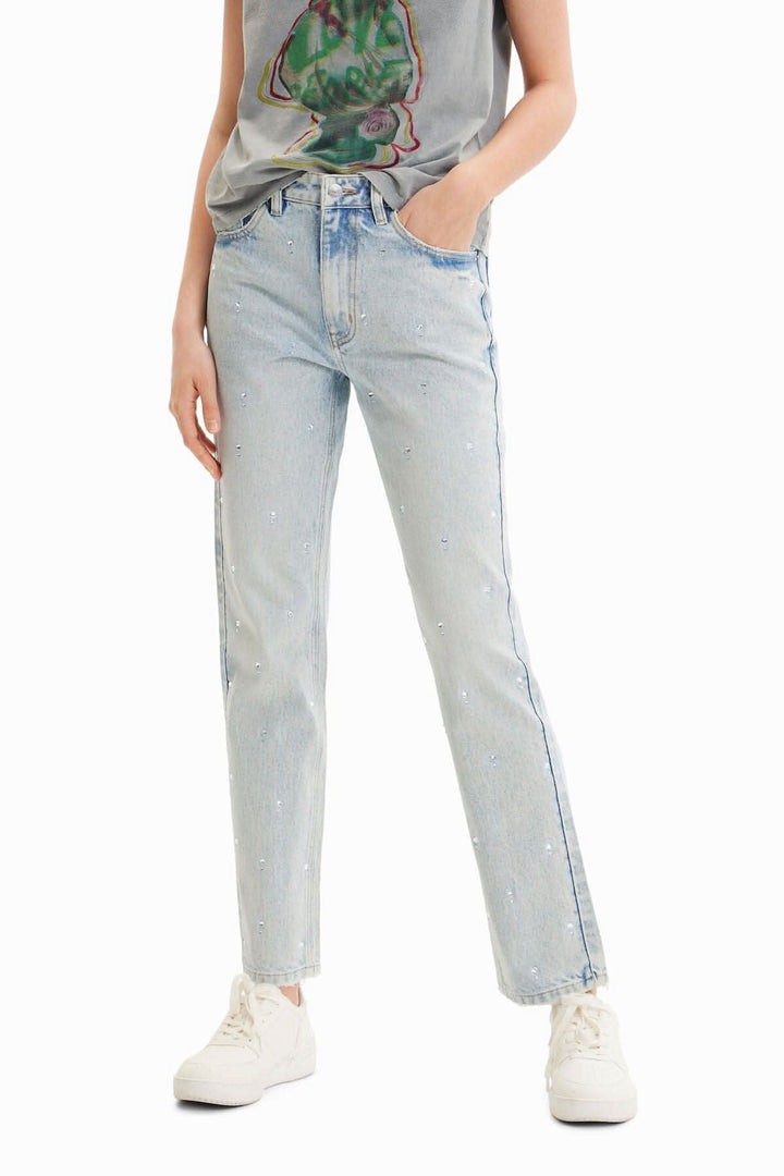 Jean droit à strass taille mi-haute, coupe légèrement cintrée et ourlet fendu, porté avec un tee-shirt.