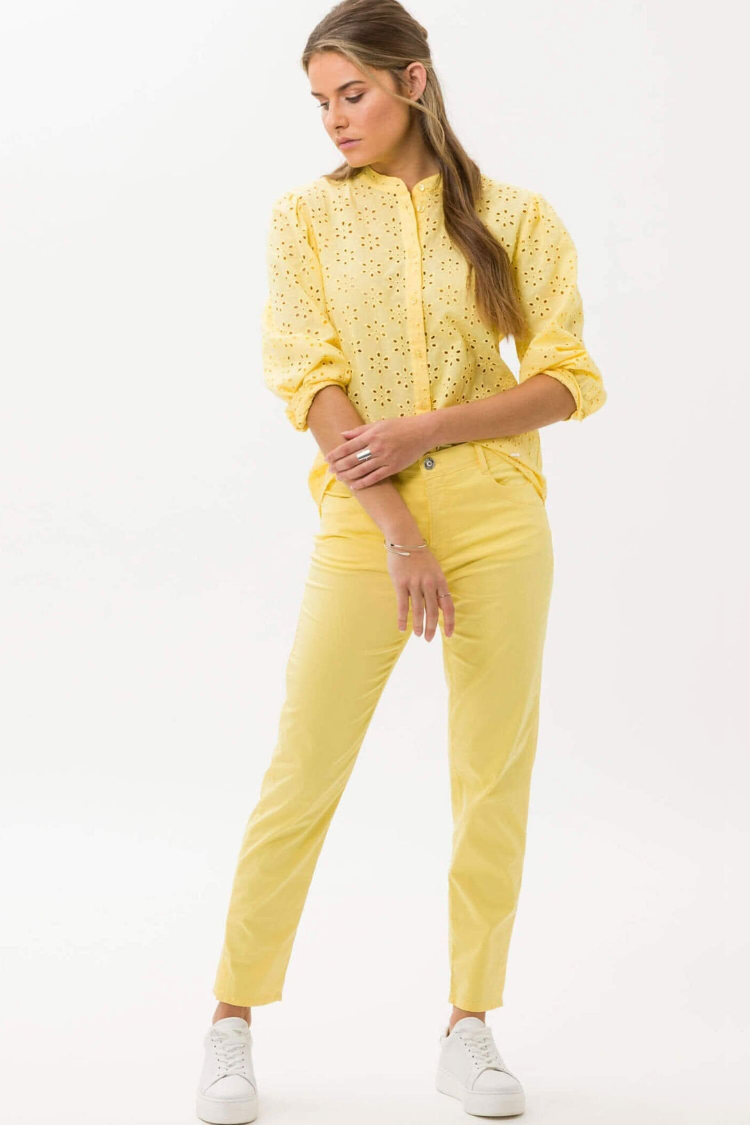Femme en chemise jaune brodée et pantalon jaune, look élégant et sportif, stylé pour un jour ensoleillé.