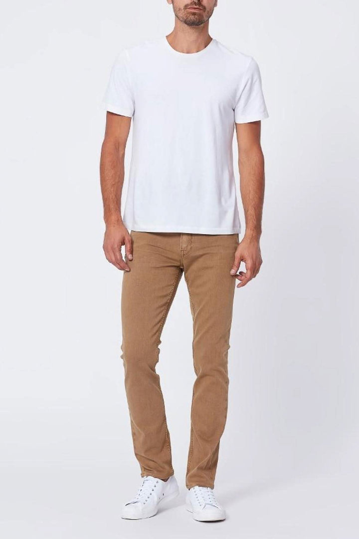 Homme portant un t-shirt blanc et un jean couleur châtaignier, look décontracté et élégant.