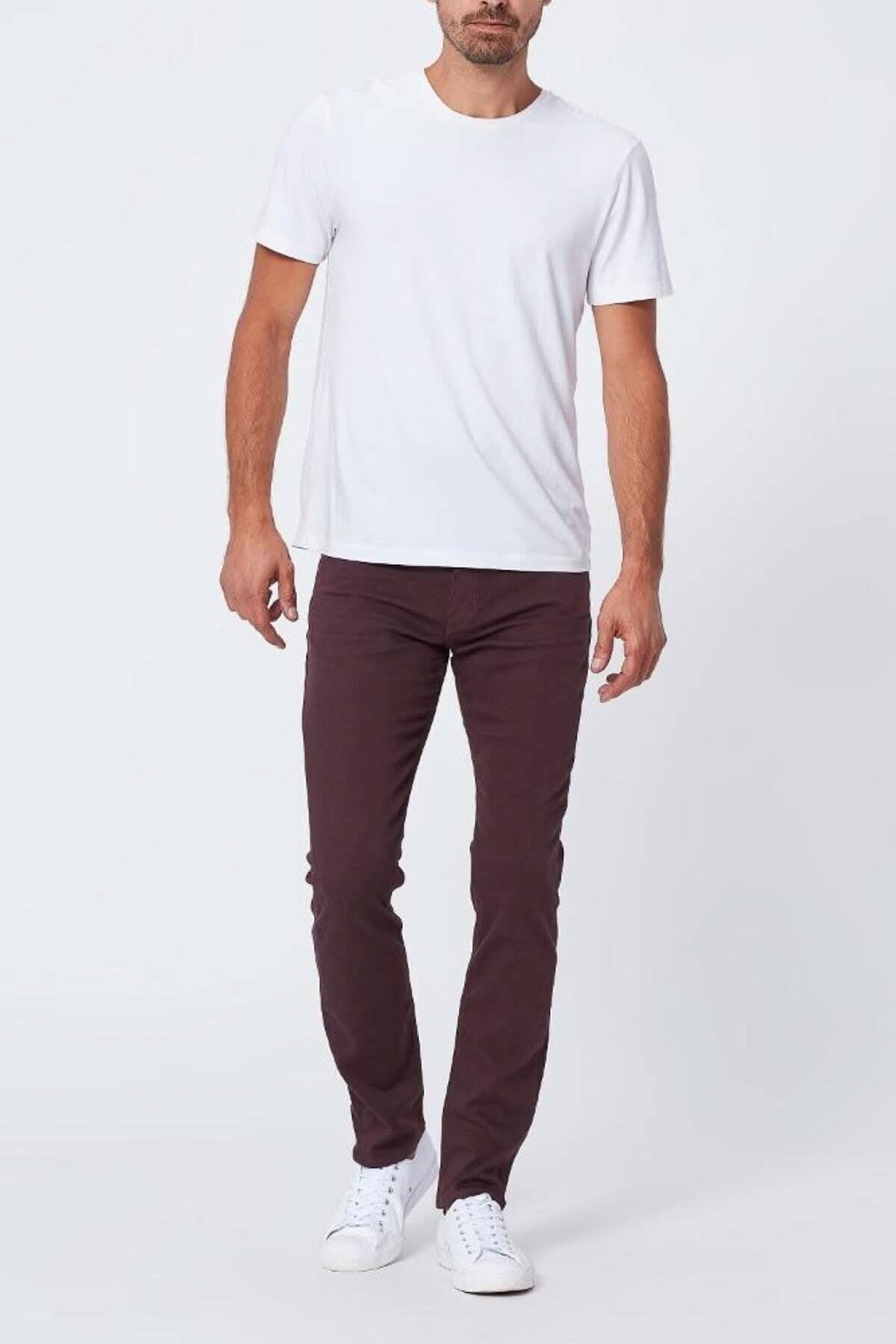 Homme portant un T-shirt blanc et un pantalon bourgogne, style slim, avec des chaussures blanches.