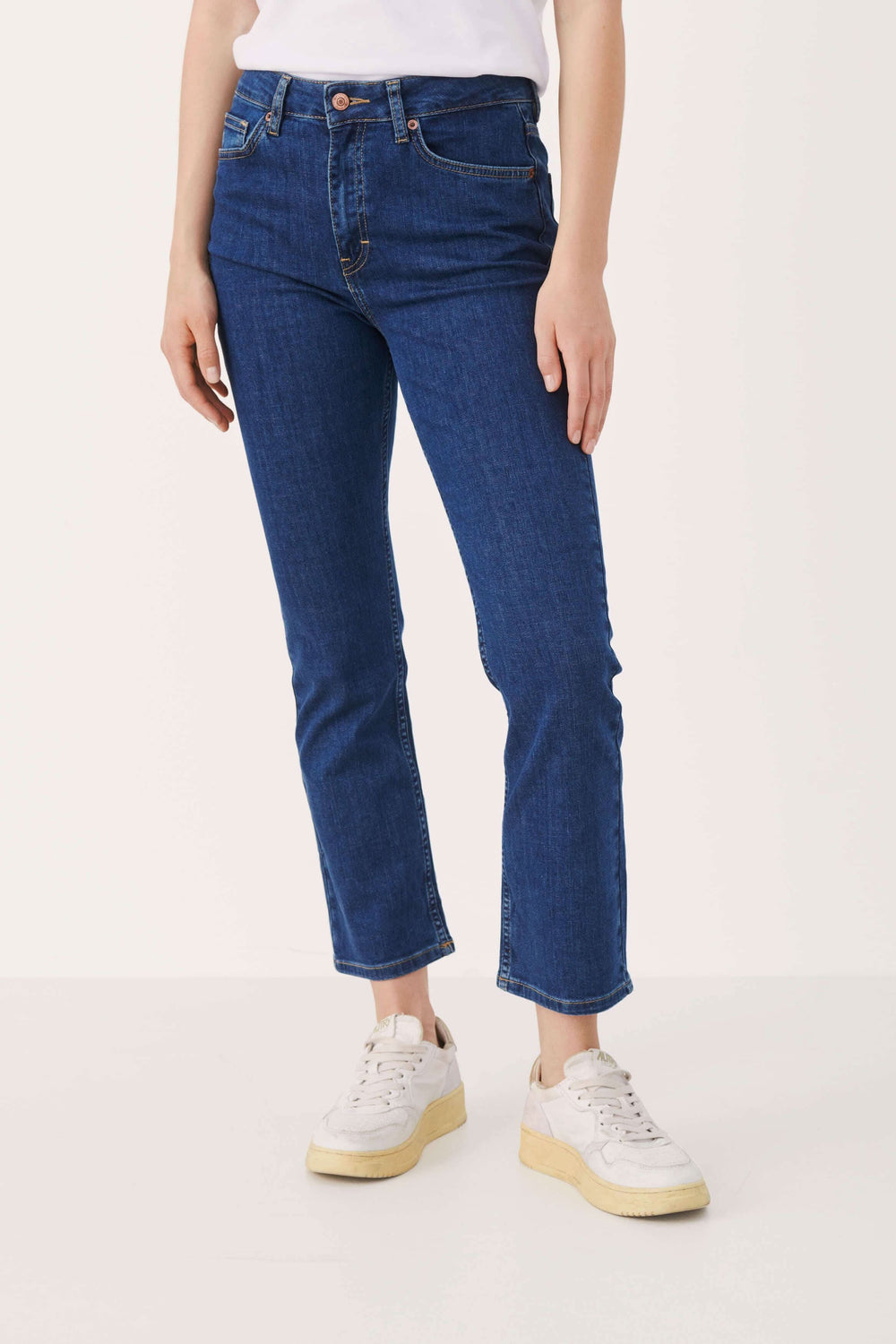 Jean ajusté à taille haute avec une jambe légèrement boot leg, longueur au-dessus de la cheville, porté par un modèle.