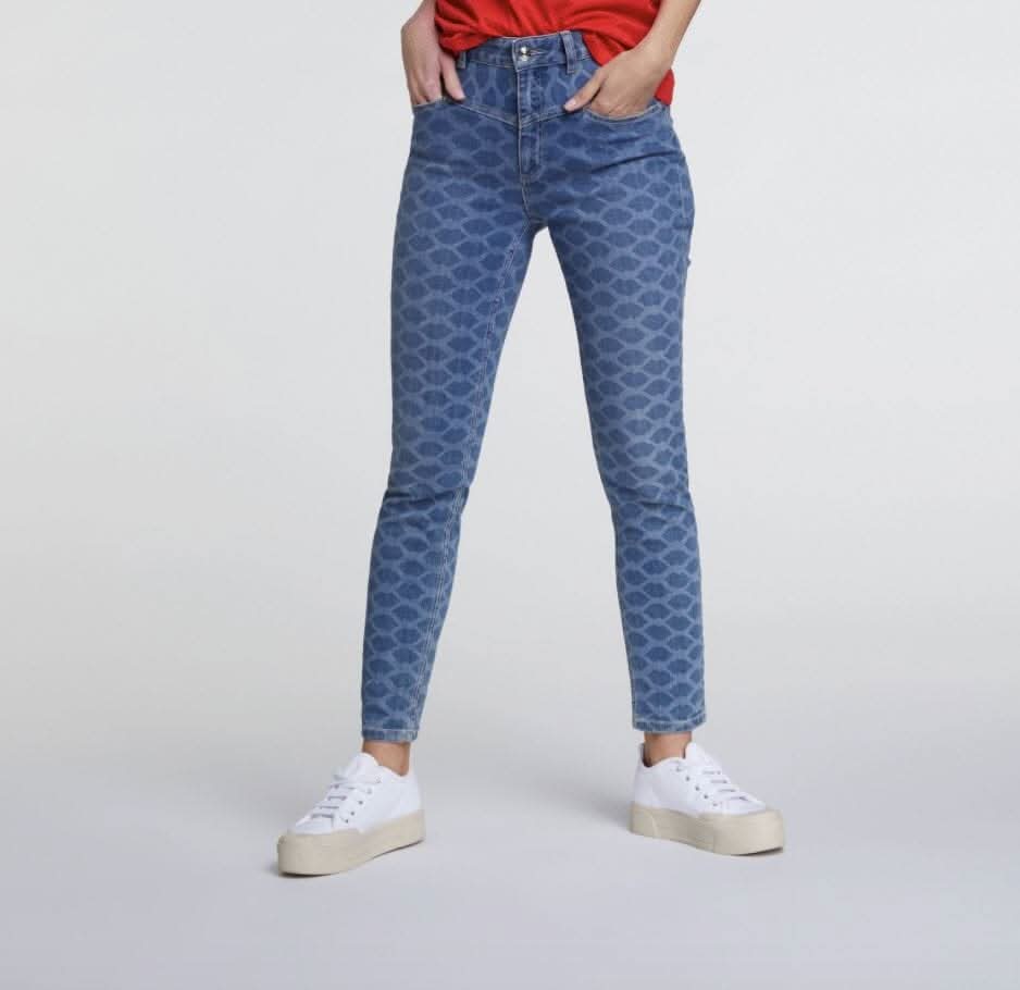 Jeans imprimé motif 'bizous' en denim, style ajusté, 98% coton, 2% élasthanne, portés avec un t-shirt rouge.