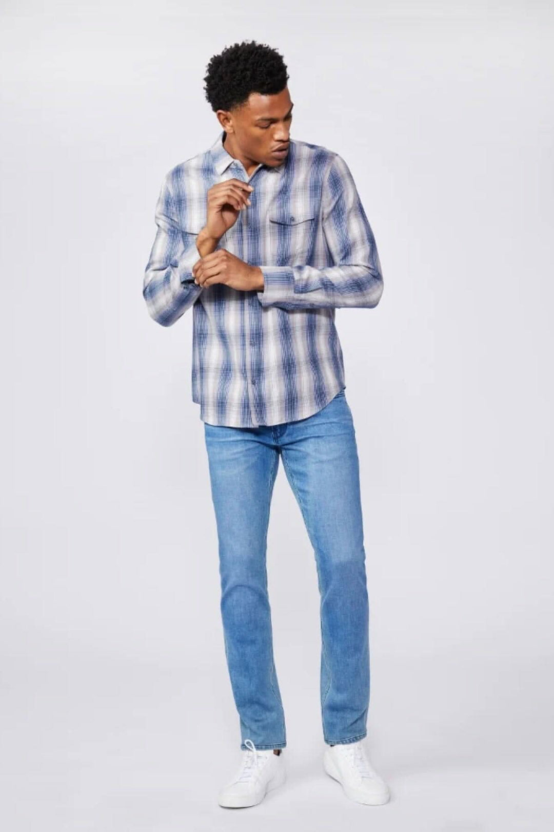Homme portant une chemise à carreaux et un jean bleu délavé, style décontracté.