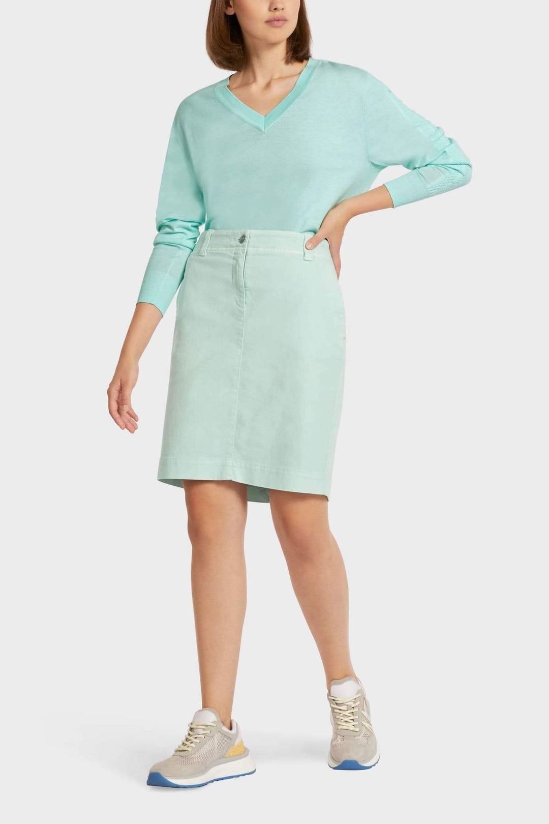 Jupe en denim bleu clair avec ceinture élastique, portée avec un pull vert menthe.